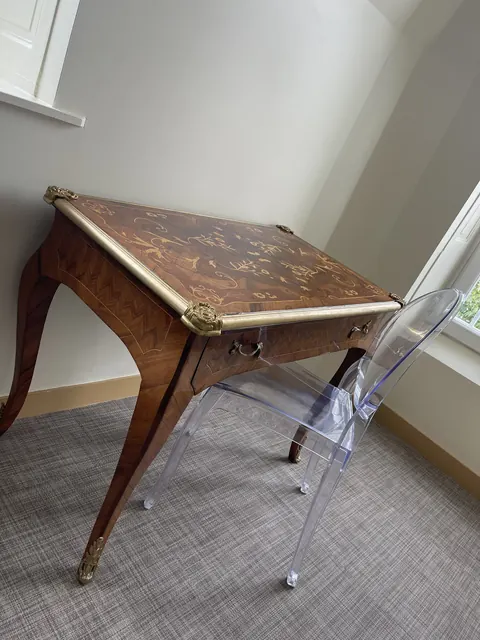 Un bureau ancien en marqueterie devant la fenêtre d'une chambre