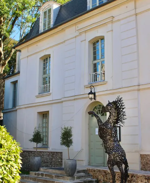 La façade blanche de l'établissement et sa sculpture de cheval