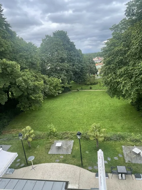 Le parc arboré et ses grands arbres, vus depuis une fenêtre à l'étage