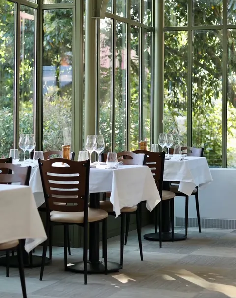 Tables nappées de blanc devant les grandes verrières