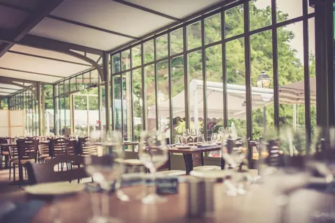 La véranda du restaurant, tables dressées face au parc